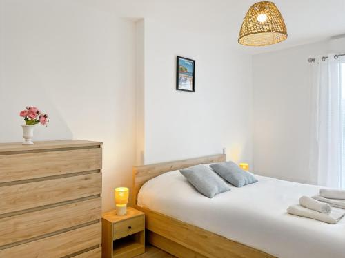 - une chambre avec un lit et une commode éclairée dans l'établissement L'échappée Belle Terrasse et Plages Saint Coulomb, à Saint-Coulomb