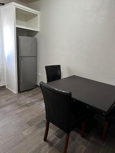 a black table and chairs in a room with a refrigerator at Hotel Mision Ferrer in San Vicente