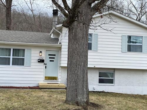 a white house with a tree in front of it at Sand Run Metro Park Getaway Home in Akron