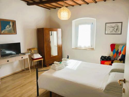 a bedroom with a white bed and a television at Appartamento Palma in Spello