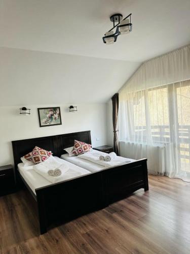 a bedroom with two beds and a large window at Casa Valea Cernei in Isverna