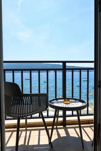 a table and a bench on a balcony with the ocean at Boka Bay Residences in Herceg-Novi