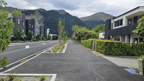 an empty street with buildings and mountains in the background at Diamond Luxury Central Queenstown in Queenstown