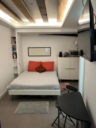 - une chambre avec un lit doté d'oreillers rouges et d'une table dans l'établissement Le nid, à Paris