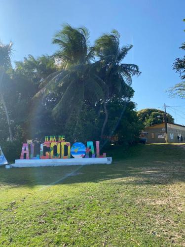a sign in a park with a palm tree in the background at Pousada Luz do Sol in Algodoal