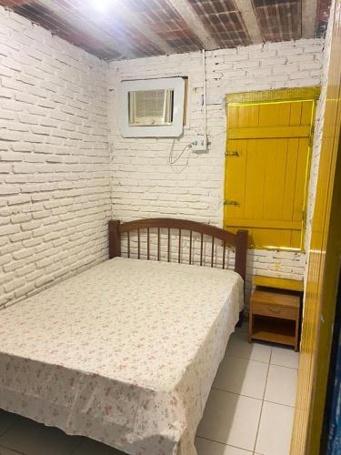a small bedroom with a bed and a yellow door at FAZENDA BOSQUE DAs PALMEIRAS in Itamaracá