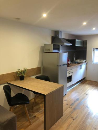 une cuisine avec une table en bois et un réfrigérateur dans l'établissement Gîte Chez Mathilde - hébergement de charme alliant cachet et modernité à 5 minutes de Colmar, à Sainte-Croix-en-Plaine