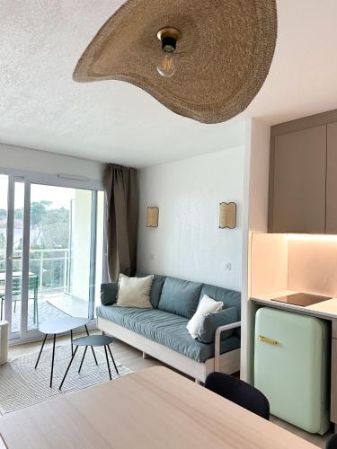 un salon avec un canapé bleu et un balcon dans l'établissement Charmant appartement dans résidence de standing, à La Baule