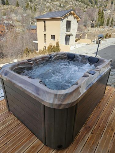a hot tub sitting on top of a wooden deck at Chalet NEUF Jacuzzi Terrasse Salle jeux proche Font Romeu in Égat
