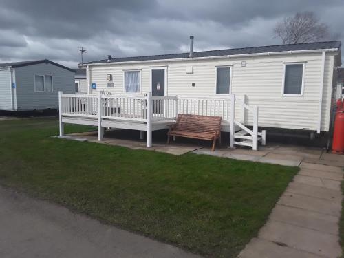 a white mobile home with a porch and a bench at Haven Skegness 20 Donna Nook in Skegness