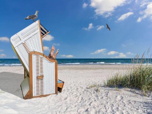 a person sitting in a chair on the beach at Appartements im Freizeitpark Weissenhäuser Strand in Weissenhäuser Strand