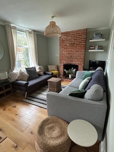 ein Wohnzimmer mit Couch und Kamin in der Unterkunft Victorian Woodbridge cottage in Melton