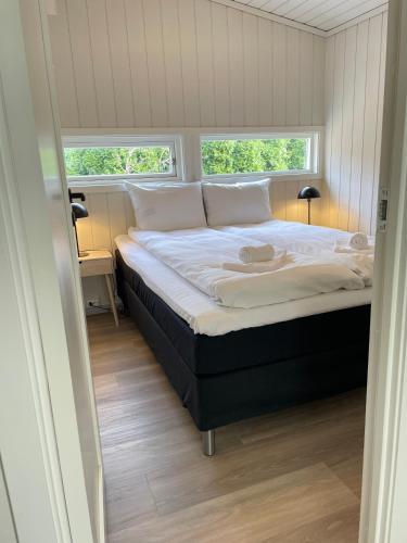 a bed in a room with two windows at Vollsnes Feriehus in Hjelle