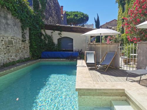 une piscine avec deux chaises et un parasol dans l'établissement Les studios de Marie, à Avignon