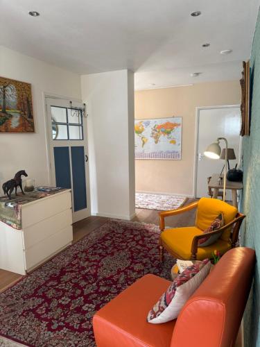 a living room with an orange couch and a yellow chair at Bij Flora in Beekbergen