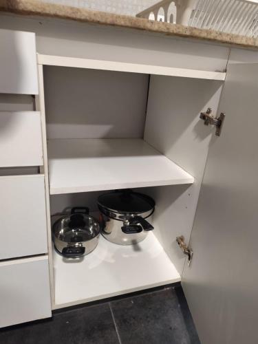a white kitchen cabinet with two pots and pans at Apartamento en Concepción con estacionamiento privado in Concepción