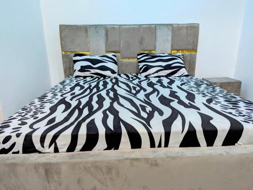 a bed with black and white sheets and pillows at White Castle Apartments in Uyo