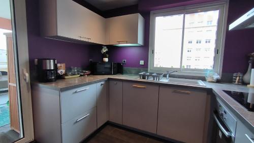 d'une cuisine aux murs violets, d'un évier et d'une fenêtre. dans l'établissement Port Royal, à Aix-en-Provence