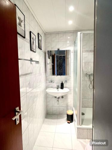 a white bathroom with a shower and a sink at Schwarzwald Apartment in Löffingen