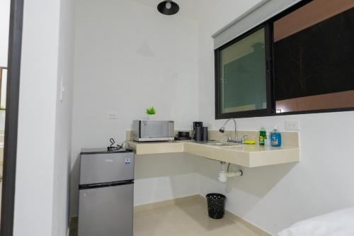 a white kitchen with a sink and a microwave at Peregrina 270 Departamentos in Motul de Felipe Carrillo Puerto