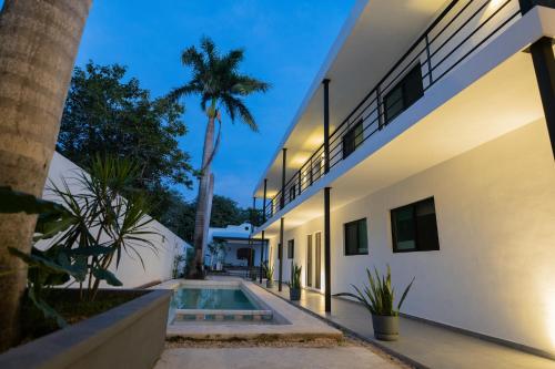 an exterior view of a house with a swimming pool and palm trees at Peregrina 270 Departamentos in Motul de Felipe Carrillo Puerto