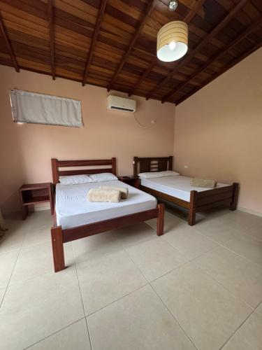 a bedroom with two beds and a wooden ceiling at Suítes Betel in Paraty