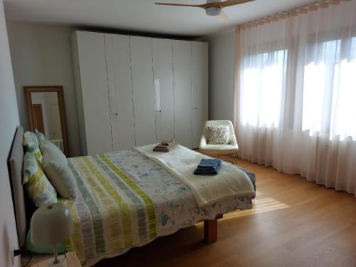 a bedroom with a bed and a chair and windows at B&B Poggio di Vento sulla via degli Dei in Monzuno