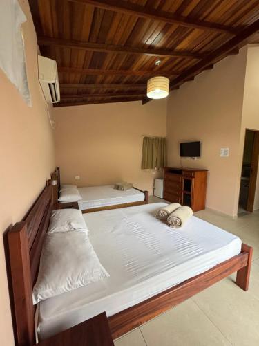a bedroom with two beds and a tv in it at Suítes Betel in Paraty