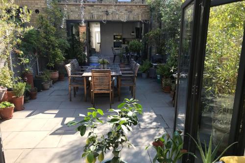a patio with a table and chairs and plants at Elegant Garden Flat - Raynes Park in Raynes Park