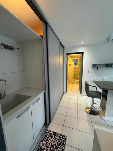 - une cuisine avec un évier, une table et une chaise dans l'établissement Dépendance avec piscine et spa partagés - plage 130 m, à Soulac-sur-Mer