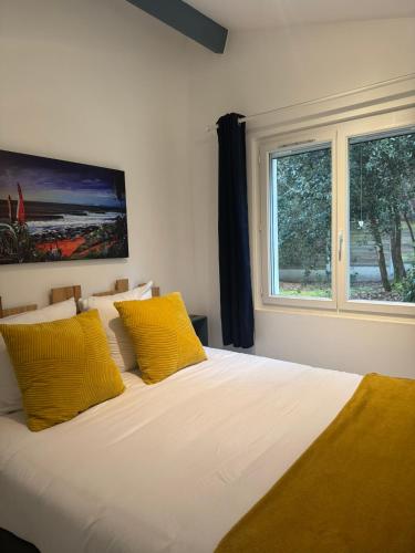 une chambre avec un lit avec des oreillers jaunes et une fenêtre dans l'établissement Dépendance avec piscine et spa partagés - plage 130 m, à Soulac-sur-Mer
