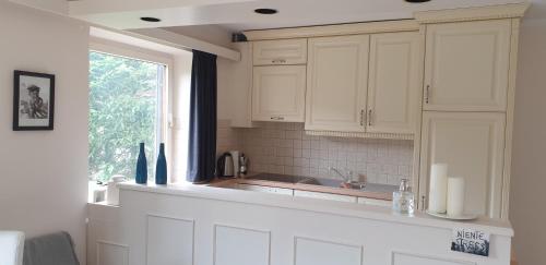 a kitchen with white cabinets and a window at Willkommen in Ihrem sonnigen Gartenapartment in Kitzbühel