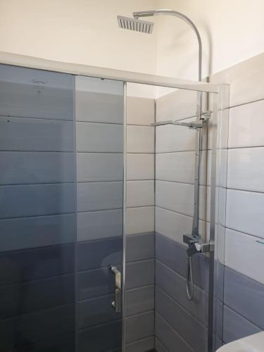 una ducha con puerta de cristal en un baño en Vila Giorgio, en Shkodër