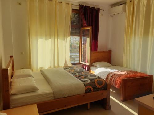 Dos camas en una habitación con ventana. en Vila Giorgio, en Shkodër