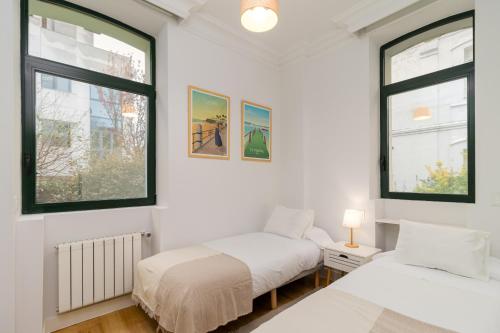 a bedroom with two beds and two windows at Vivienda en el Sardinero in Santander