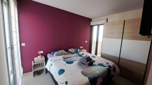 a bedroom with a large bed with purple walls at Case de bamboo in Benijófar