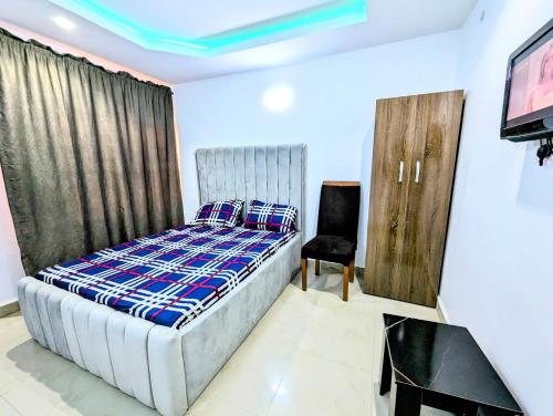 a bedroom with a bed and a tv and a chair at White Castle Apartments in Uyo