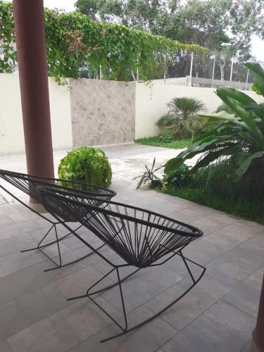 a black chair sitting on a patio with a plant at Casa Quetzal in Peñita de Jaltemba