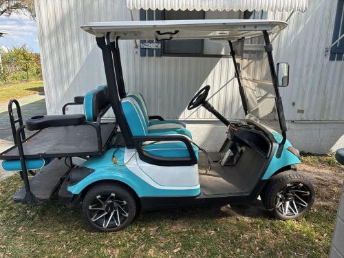 a blue and white golf cart parked in the grass at The Lake House on Lake Rosalie in Lake Wales