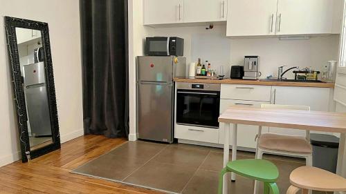 une cuisine avec des appareils en acier inoxydable et une table avec des chaises dans l'établissement Charmant 2 pièces calme proche Paris, à Cachan