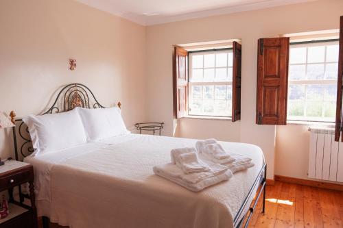ein Schlafzimmer mit einem weißen Bett mit Handtüchern darauf in der Unterkunft Casa da Chitas in Ponte de Lima