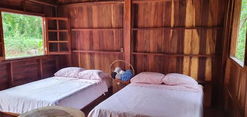 two beds in a wooden room with two windows at Cabaña la ira in Santa Maria Huatulco