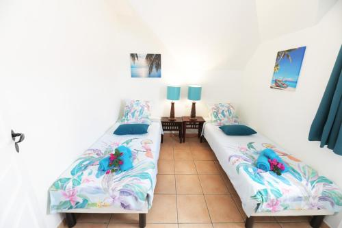 two beds in a room with white walls at Passion Martinique T3 6 pers 72 m2 Pierre&Vacances in Sainte-Luce