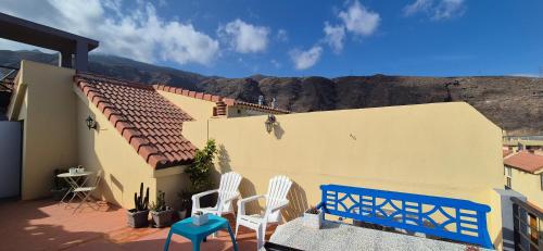 Una casa con dos sillas y un banco azul en un patio. en Vistas mar Candelaria 120 meters, en Candelaria