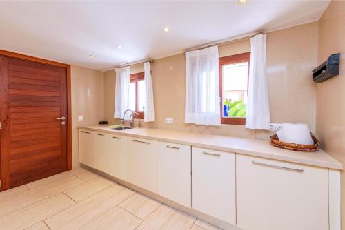 a kitchen with white cabinets and a wooden door at Villa Azumar, piscina, jardín in Sant Carles de Peralta