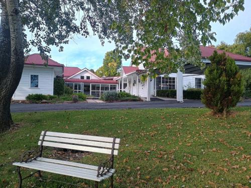 a park bench sitting in the grass under a tree at Moore Park Inn in Armidale