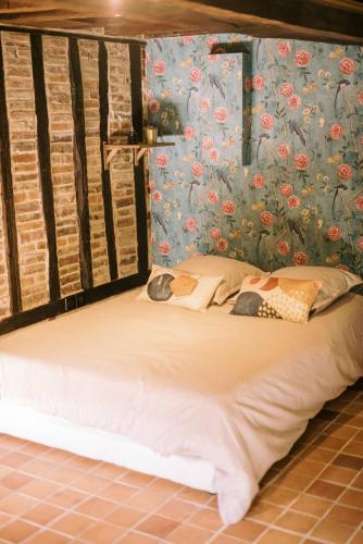 a bed in a room with a wall with flowers at Le Refuge d'Alfred, centre Pont-Audemer in Pont-Audemer