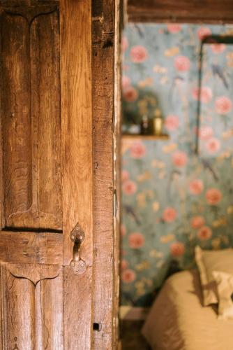 a wooden door in a bedroom with a floral wallpaper at Le Refuge d'Alfred, centre Pont-Audemer in Pont-Audemer