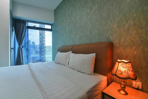 a bedroom with a bed with a window and a lamp at Eaton Residence KLCC in Kuala Lumpur