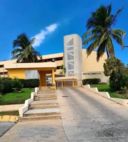 a building with a palm tree in front of it at Lecheria con vista al mar in Morro de Barcelona